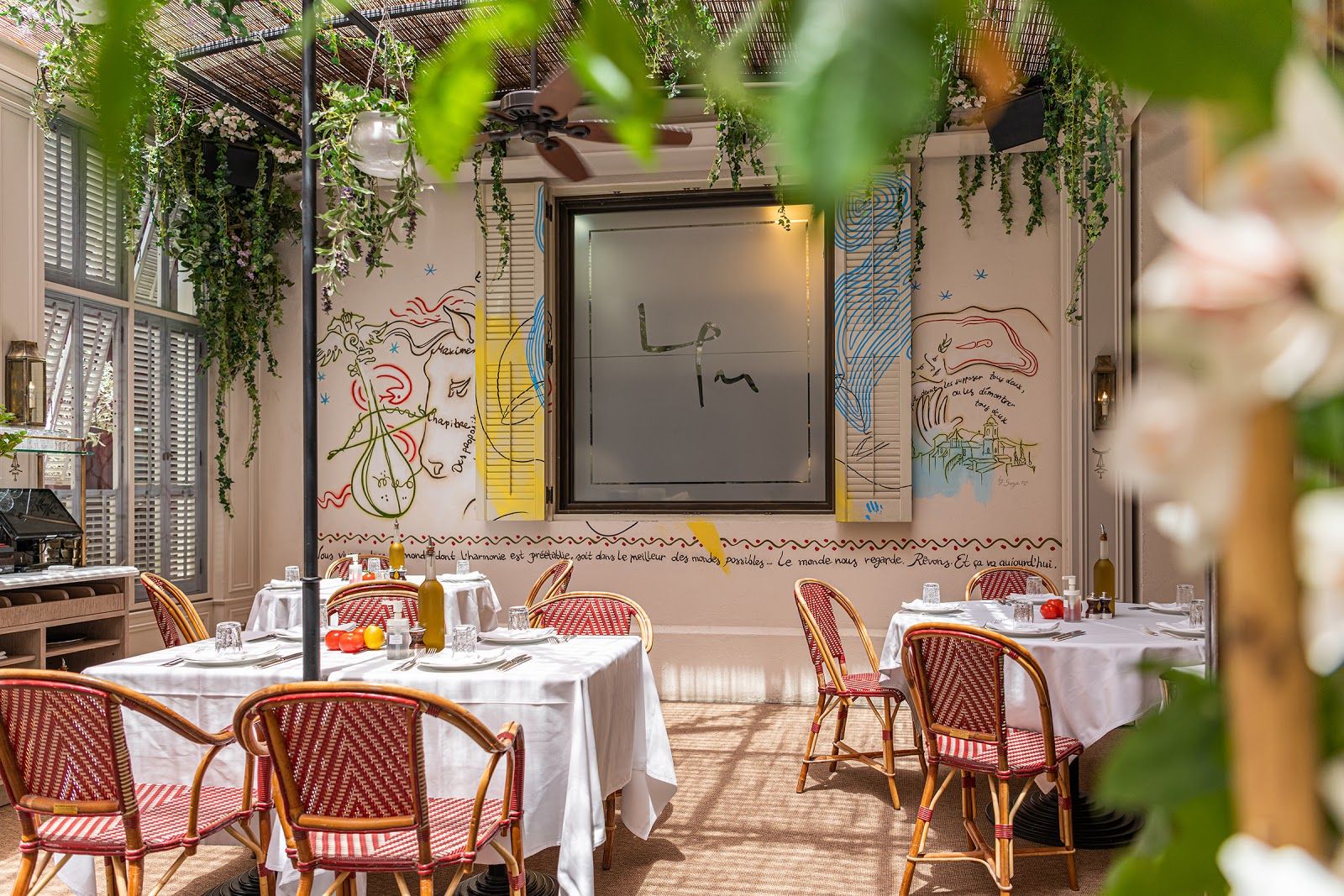 French Mediterranean restaurant with whitewashed walls, olive trees and warm ambient light — LPM DIFC Dubai style