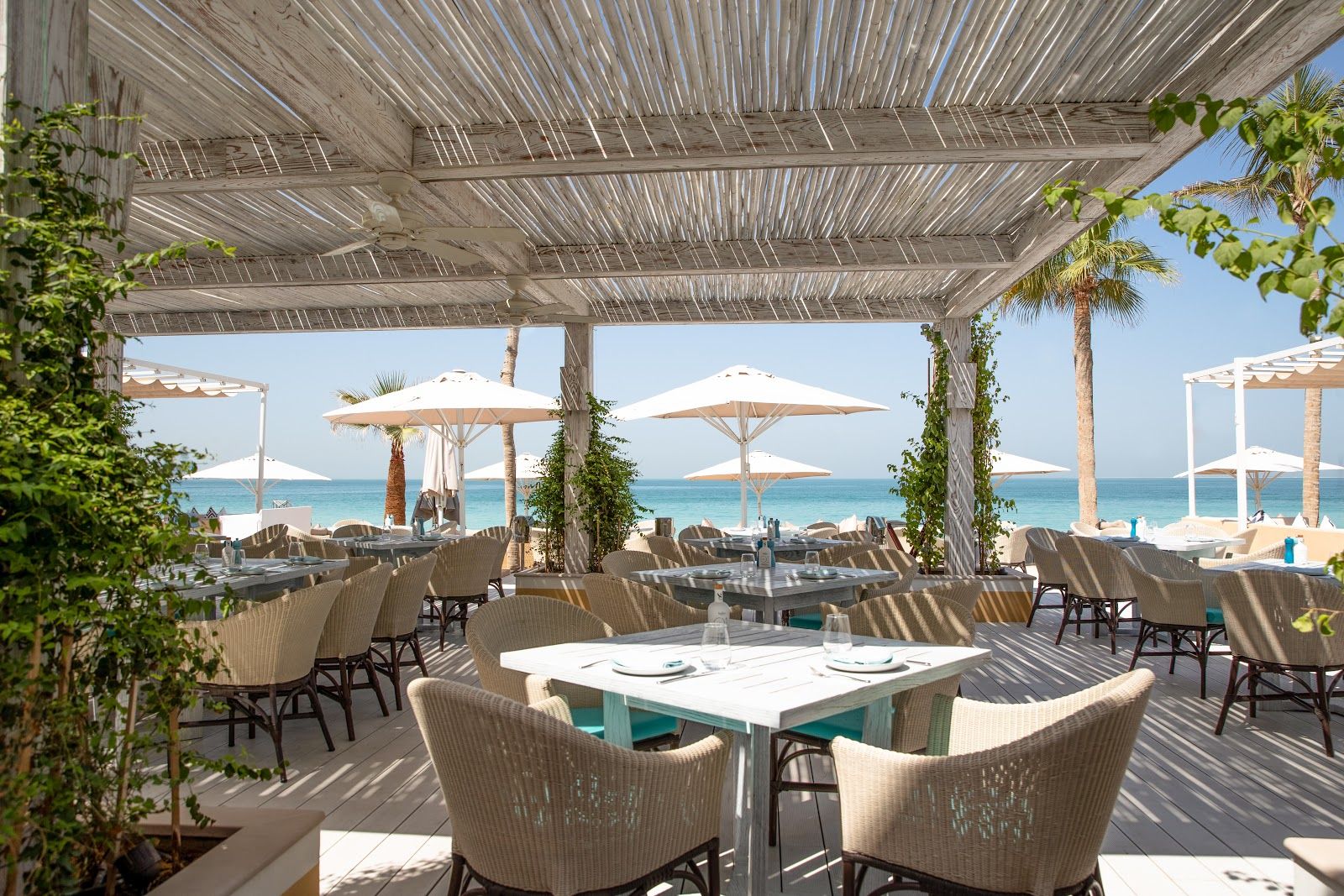 Outdoor beachfront restaurant at sunset — Madinat Jumeirah waterway with Burj Al Arab view